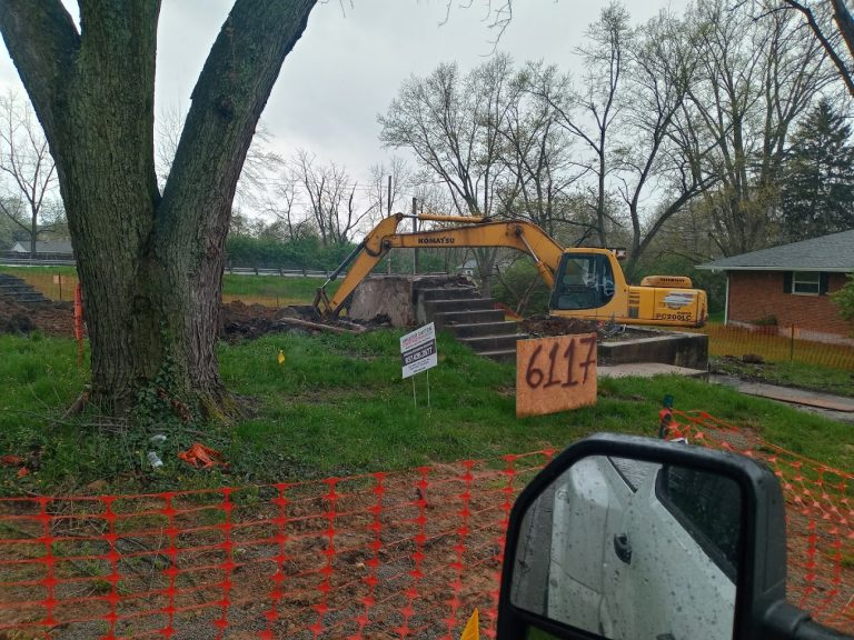 Excavator at a fenced work site with concrete steps