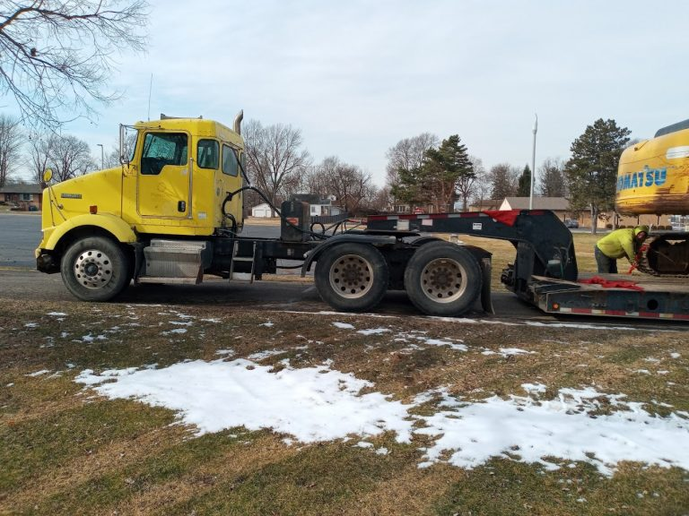 Semi truck and trailer being loaded with an excavator