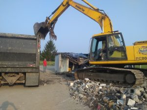 Excavator clearing concrete and demolition debris