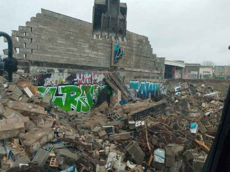 Excavator taking down a block wall